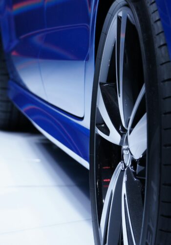Close-up shot of a blue car highlighting the stylish alloy wheel. Perfect for automotive enthusiasts.
